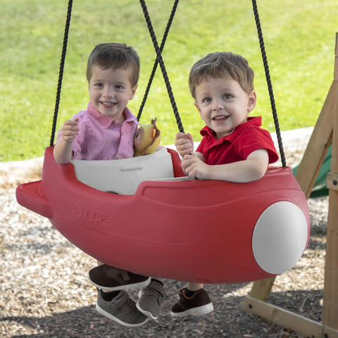 Rocket Swing For Two Outdoor Baby Swing With Weather Resistant Rope Attaches To Your Playset In The Backyard For Toddlers 9 Months To 3 Years Old Safe Buckle Comfort And Easy No Fuss Setup For Kid Friendly Fun; Two toddlers in red rocket-shaped swing on playset outdoors.