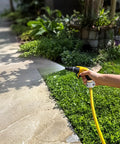 Person watering garden with hose spray nozzle outdoors