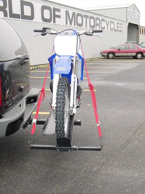 Front view of Dirt Bike Hitch Carrier With Ramp for 2 Inch Class III and IV Hitches, mounted on a vehicle, securing a blue dirt bike.