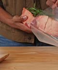 Person placing meat with rosemary into Heavy Duty Quart Vacuum Seal Bags 44 Pack With 30 Percent Extra Thickness, Leakproof.