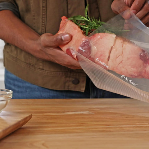 Person placing meat with rosemary into Heavy Duty Quart Vacuum Seal Bags 44 Pack With 30 Percent Extra Thickness, Leakproof.