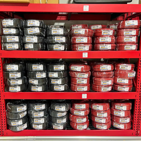 Top Shelf Heavy Duty DC PV Cable 100 FT Roll in red and black colors displayed on shelves for solar panel applications.