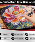 Hand holding tube of Clear Glue With Precision Tip 15ml 50 Pack for gluing rhinestones on colorful flower canvas art.