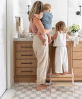 Mom and child using the Sturdy Wooden Two Step Stool For Kids Featuring Quick Fold Design And Rock Solid Base Perfect For Potty Training Bathroom Sinks Kitchen Counters And Closet Reach In Real Cool Pink.