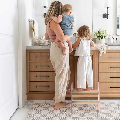 Mom and child using the Sturdy Wooden Two Step Stool For Kids Featuring Quick Fold Design And Rock Solid Base Perfect For Potty Training Bathroom Sinks Kitchen Counters And Closet Reach In Real Cool Pink.