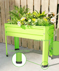 Green elevated raised garden bed with legs heavy duty galvanized steel planter box for vegetables, flowers, and herbs on patio.