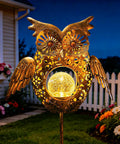 Bronze Solar Owl Garden Stake Lights For Lawn And Pathway glowing in a yard at night, featuring crackled glass and decorative wings.