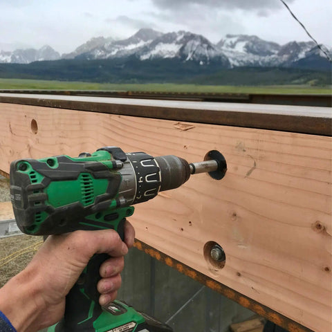 Person using Hammer Drill With Brushless Motor, Tool Only No Battery, 36V MultiVolt on wood beam outdoors with mountain view.