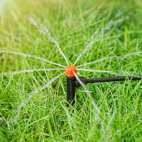 Adjustable Drip Irrigation Emitters Kit With Five Inch Stakes Fifty Pack For Quarter Inch And Four To Seven Millimeter Tubing 360 Degree Water Flow Plug And Play Easy Connect Locking Drippers For Garden Plants And Flowers in use on grass
