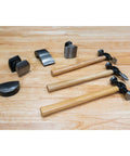 7-Piece Auto Body Repair Kit With Carbon Steel Hammer Heads And Dollies On Wood Handles displayed on wooden surface