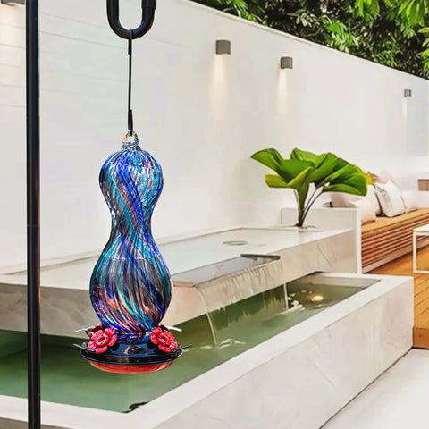 Outdoor Hand Blown Glass Hummingbird Feeder With 24 Oz Capacity And Four Feeding Ports hanging in a garden setting
