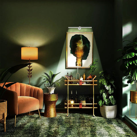 Living room with dimmable picture light illuminating artwork above bar cart, showcasing modern decor and plants