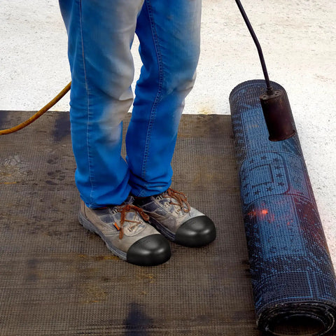 Man wearing steel toe cap covers for shoes and work boots in construction setting with protective gear