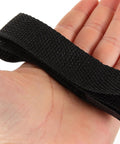 Hand holding black nylon strap for Adjustable Garden Aerator Shoes Straps Eight Pack For Lawn Care Spiked Sandals That Create Tiny Holes