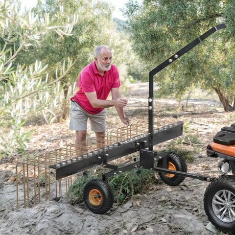 60 Inch Tow Behind Pine Needle Rake For Lawn Mowers, ATVs, And Tractors With 24 Tines, shown in use on rough terrain