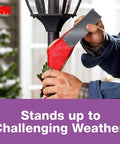Person using No Residue Duct Tape 1.88 Inch By 20 Yards Grey 2420A Heavy Duty Adhesive on outdoor pole in challenging weather.