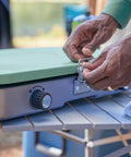 Close-up of hands handling the Three In One Outdoor Camp Stove With Removable Cast Iron Grill And Griddle 24,000 BTUs Portable Tailgate Ready Cooker