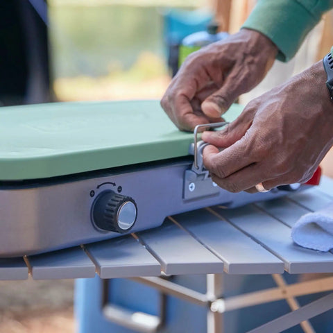 Close-up of hands handling the Three In One Outdoor Camp Stove With Removable Cast Iron Grill And Griddle 24,000 BTUs Portable Tailgate Ready Cooker