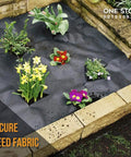 Raised garden bed with black weed barrier fabric and various flowering plants for garden installation.