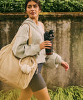 Woman walking with Rock Solid Leakproof Shaker Bottle With Connected Hinge Cap And Fast Flow Spout Built Tough For Gym Sessions And Trail Runs 20 Oz Tritan Protein Mixer.