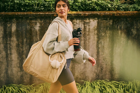 Woman walking with Rock Solid Leakproof Shaker Bottle With Connected Hinge Cap And Fast Flow Spout Built Tough For Gym Sessions And Trail Runs 20 Oz Tritan Protein Mixer.
