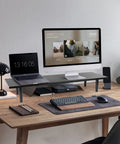 Dual Monitor Stand Riser For Desk With Adjustable Length 32 To 40 Inches Space Saving Desk Shelf Organizer For Two Screen Setup Large Monitor Riser Stand For Computer Laptop PC Printer TV Black shown on a wooden desk holding a laptop and monitor.