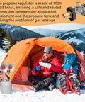 Man camping with orange tent in snow using Tank Top Propane Regulator Valve Kit For Portable Heaters That Plays Nice With SunRite SRC15T SRC30T Dura Heat GR121 HD15 And MH Series Tank Top Heaters Replacement Parts connected to heater.
