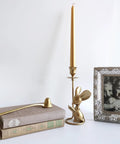 Image showing a long handled cast iron candle snuffer extinguisher tool for safe flame control and old school rustic vibe 9.8 inch reach candle care accessory next to a golden candle holder and framed photo.