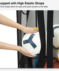 Hands placing soccer balls in black Ball Storage Organizer Basket For Garage, Gym, Or Playroom, with elastic front access
