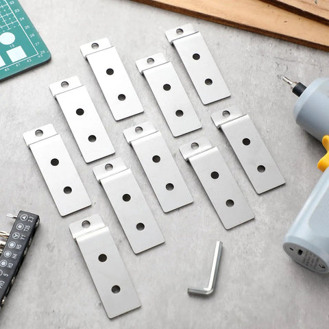 Twenty Pack Slatwall Mount Backplates For Metal Wall Panels Heavy Duty Steel Brackets With Three Pre Drilled Holes For Easy Secure Displays Slatwall Compatible Silver arranged on a surface with tools nearby.