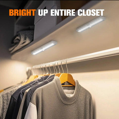 Motion Sensor LED Lights 6 Pack Battery Operated With 10 LEDs Per Bar illuminating clothes in a closet.