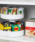 Smooth Rotating Two Tier Snack Carousel Countertop Organizer holding snacks in a tidy white resin design in a pantry.