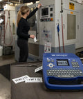 Hella Tough Portable Label Printer With Auto Cut And Badass Build on workstation with labels RW15 and RW20 in machine shop.