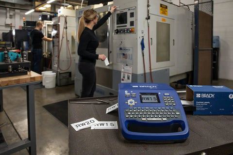 Hella Tough Portable Label Printer With Auto Cut And Badass Build on workstation with labels RW15 and RW20 in machine shop.