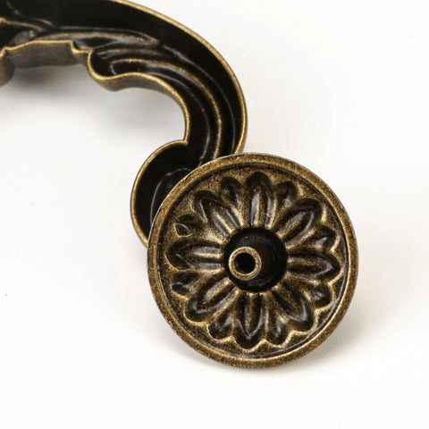 Close-up of antique yellow bronze handle end showing ornate design of Four Piece 150mm Center Drawer Pull Handles In Zinc Alloy Rustic Vintage Style Drop Down Bail Swing Dresser Cabinet Pulls With Antique Yellow Bronze Finish For Kitchen Cabinets And Furniture.