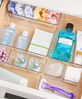 No Sweat 44 Piece Clear Plastic Drawer Organizers Set With Adjustable Vanity Trays For Bathroom Kitchen Office Craft Storage Makeup Cosmetic Tidying in a drawer with assorted beauty products.