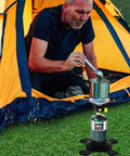 Man using Ultra Portable Propane Camping Stove With Quick Ignition outside tent for outdoor cooking.