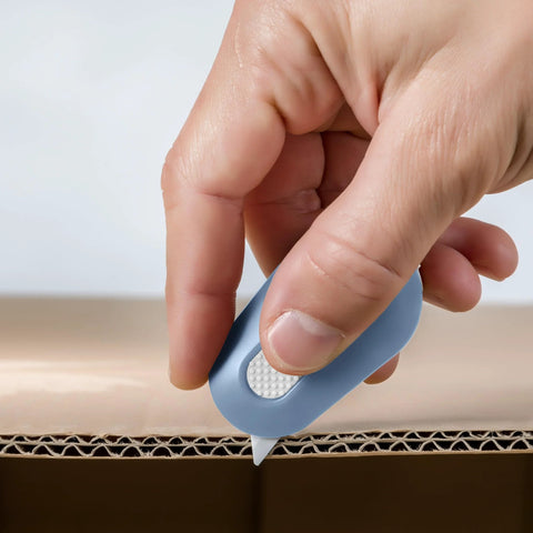 Front view of blue Slice mini box cutter with retractable ceramic blade cutting cardboard.