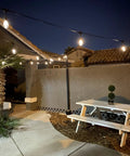 Ambience Pro 48 Ft Solar Outdoor String Lights With 15 Shatterproof 1W LEDs illuminating a backyard patio with a cozy bistro vibe