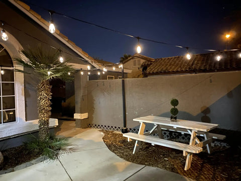 Ambience Pro 48 Ft Solar Outdoor String Lights With 15 Shatterproof 1W LEDs illuminating a backyard patio with a cozy bistro vibe