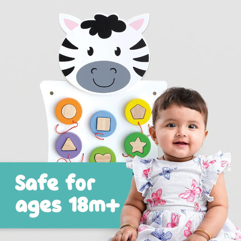 Zebra Activity Wall Panel For Toddlers Ages 18 Months Plus with hardwood shapes, shown with a smiling toddler in a butterfly dress.