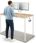 Rock Solid Electric Standing Desk Gliding Smoothly On Ultra Quiet Quad Motors Sixty Three Inch Worktop with dual monitors and accessories.