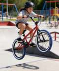 Child jumps on Freestyle 20 Inch BMX Bike For Beginners Kids 8 To 15 Red Frame With Blue Tires Kid Friendly Ride For Boys And Girls
