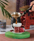 Hand Hammered Copper Turkish Coffee Pot 12 Oz With Wooden Handle being used to pour coffee into a cup on a table