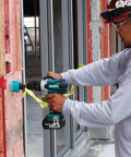 Worker using Rock Solid Eighteen Volt Cordless Hammer Driver Drill Kit featuring killer torque for drilling into wood.