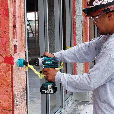 Worker using Rock Solid Eighteen Volt Cordless Hammer Driver Drill Kit featuring killer torque for drilling into wood.