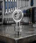 3/4 Inch Steel Heim Joint Rod End With Two Nuts And Right Hand Thread For Quick Installation on a stainless steel workbench.