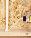 Applying Tough As Nails Mouse Proof Expanding Foam Sealant around pipe hole for pest prevention.