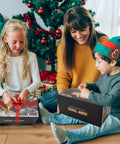Children opening boxes of Remote Control Dump Truck Toy with Blue Warning Lights by Christmas tree