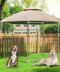 Outdoor chain link fenced dog kennel with two dogs, canopy cover, and wooden fence backdrop in a grassy yard.
